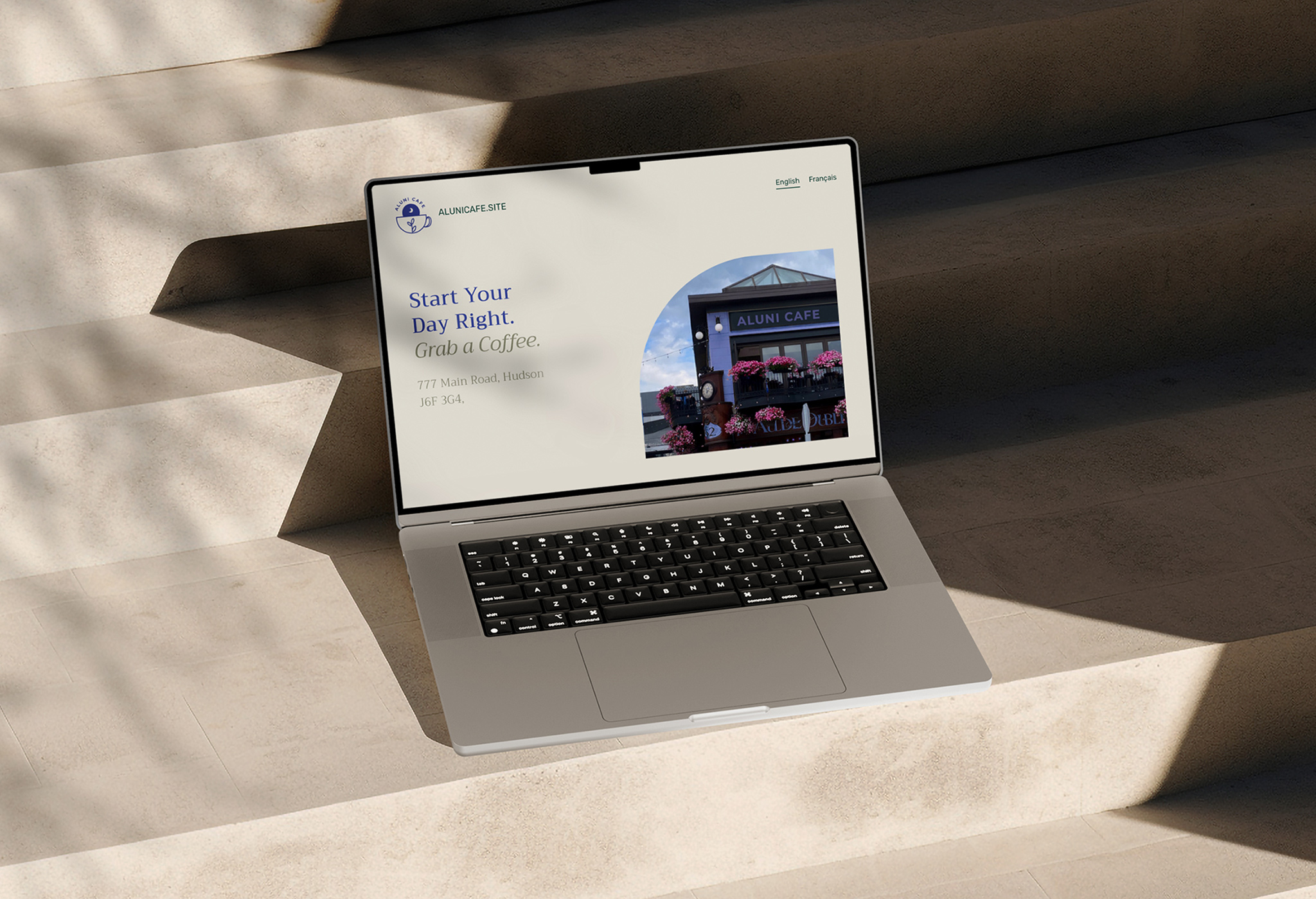 Mockup of a laptop sitting on concrete stairs. The laptop is displaying the home page of a website I created for an imagined cafe.